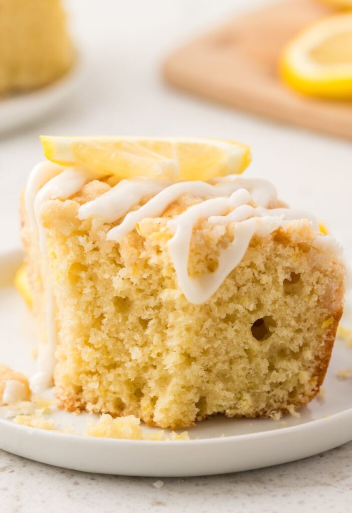 A piece of lemon cake with glaze and a crumble on top