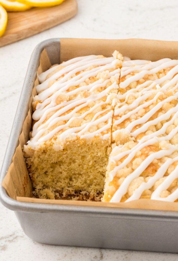A pan of lemon coffee cake with a piece taken out of it.