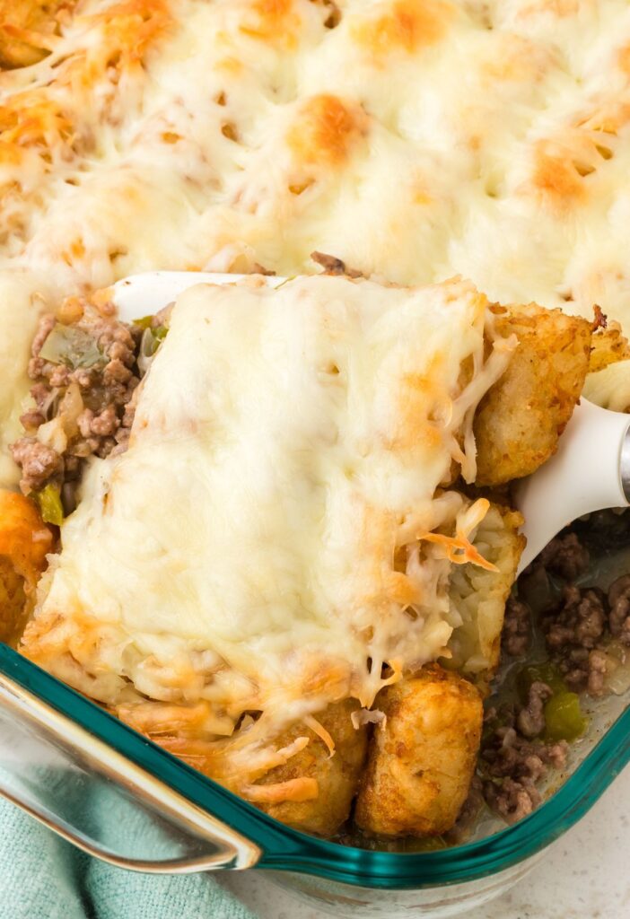 A tater tot casserole with a scoop inside of it.