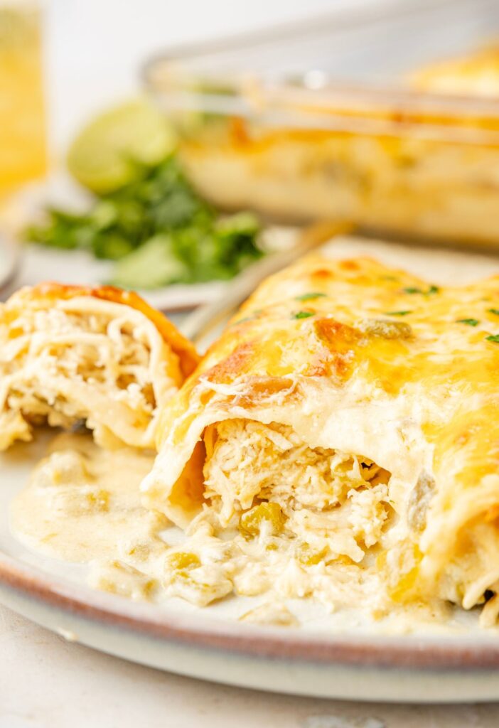 A chicken enchilada on a plate with a fork