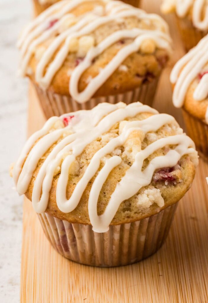 Side view of a strawberry muffin with a crumble topping and glaze.
