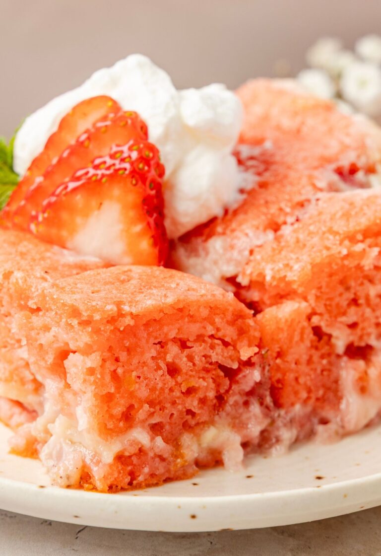 A slice of the strawberry cake with whipped cream and a strawberry on top of it.