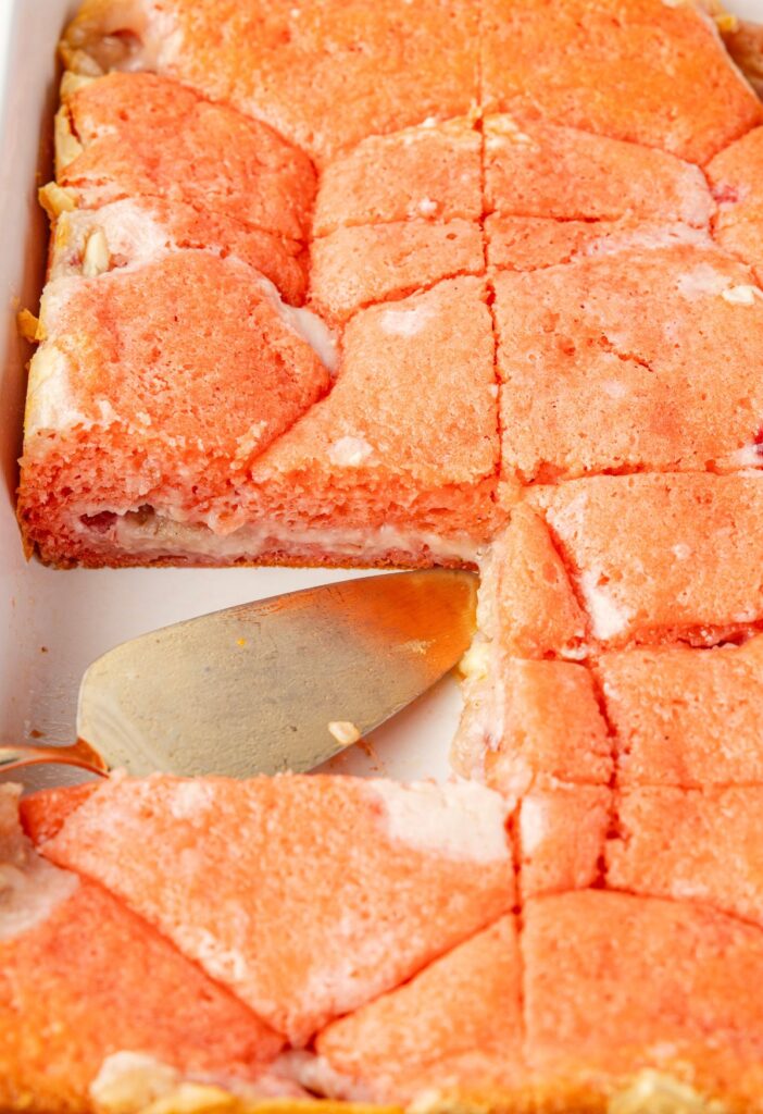 The pan of cake with a slice cut out of it and a serving spatula in it.