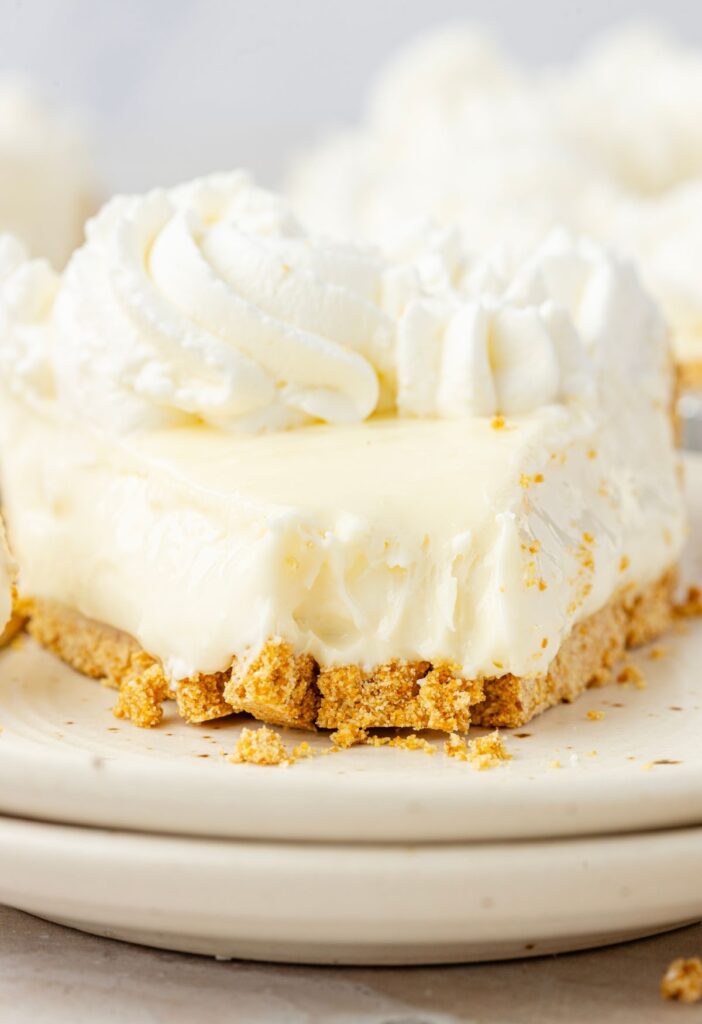 A front view of a slice of cheesecake with a fork bite taken out of it.