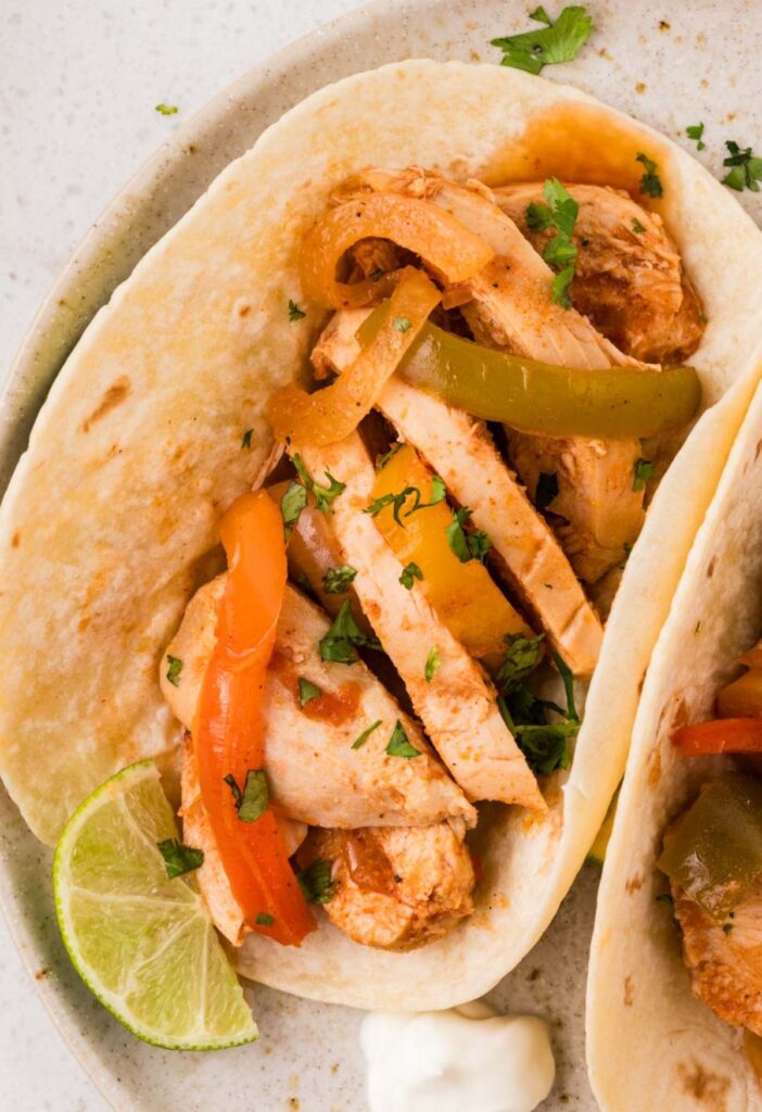 A flour tortilla with chicken fajita filling inside of it