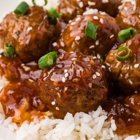 A plate of white rice with orange chicken meatballs