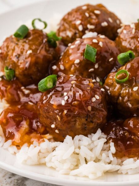 A plate of white rice with orange chicken meatballs
