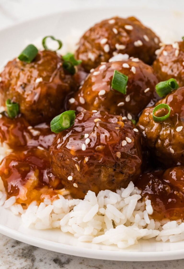 A plate of white rice with orange chicken meatballs
