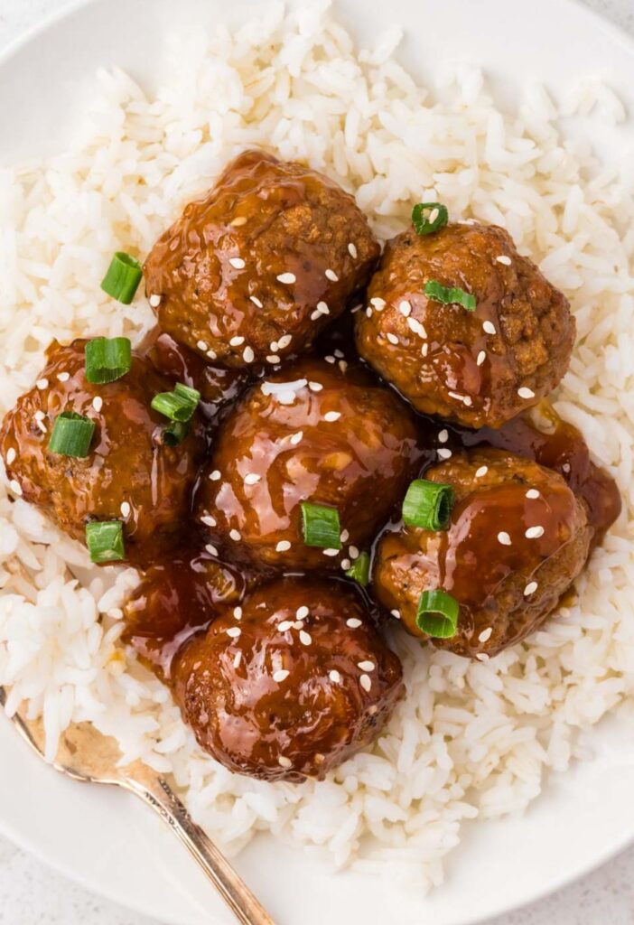 Serving of meatballs on top of white rice with a fork.
