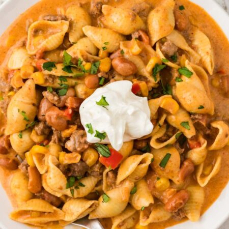 A white plate of the cheesy taco pasta with sour cream on top.