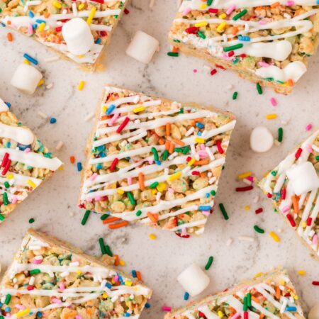 Squares of the Rice Krispie treats with sprinkles and mini marshmallows around them.