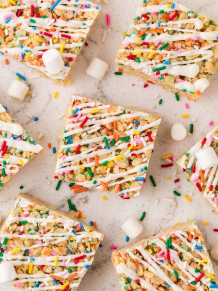 Squares of the Rice Krispie treats with sprinkles and mini marshmallows around them.