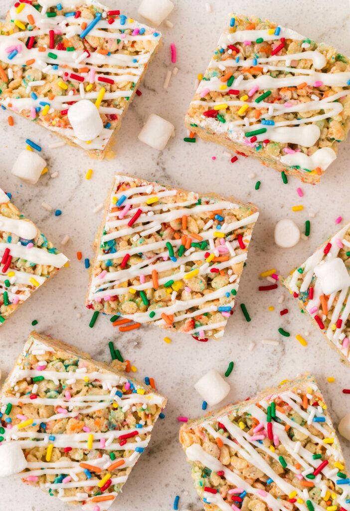 Squares of the Rice Krispie treats with sprinkles and mini marshmallows around them.
