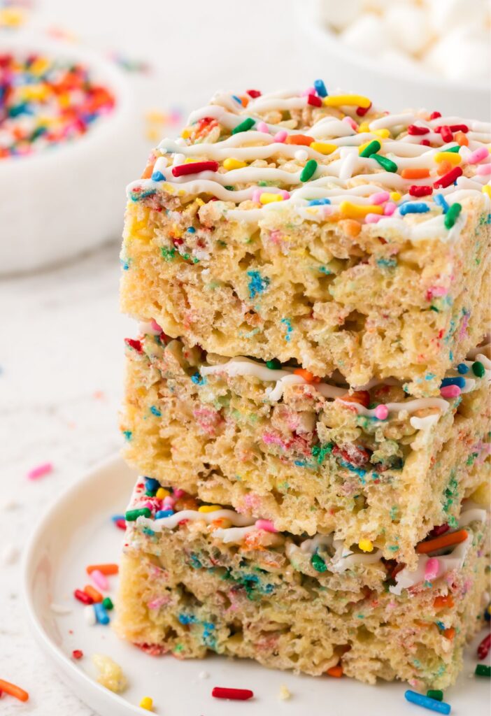 Stack of funetti Rice Krispie treats with sprinkle and white chocolate on top.