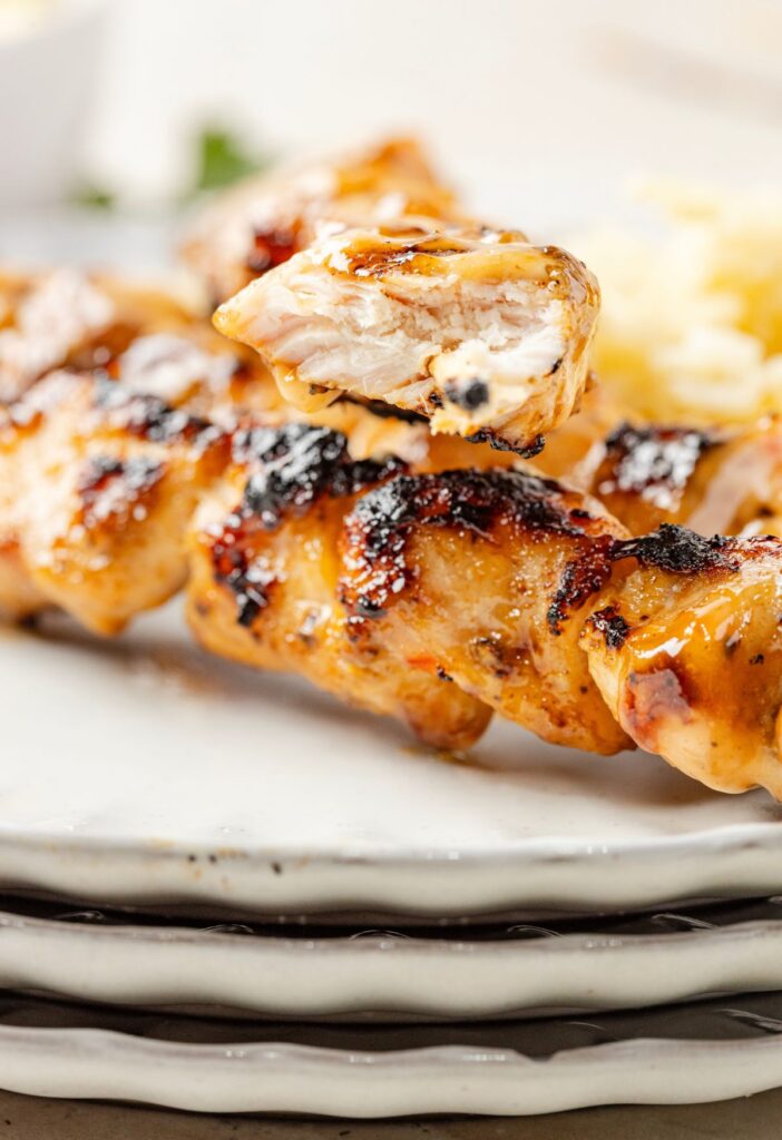 Chicken skewers cooked on a white serving plate.