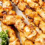 Cooked chicken skewers with a bang bang sauce glaze.