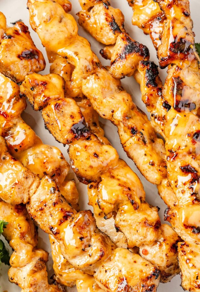 Chicken skewers on a plate with grill marks from cooking on the grill.