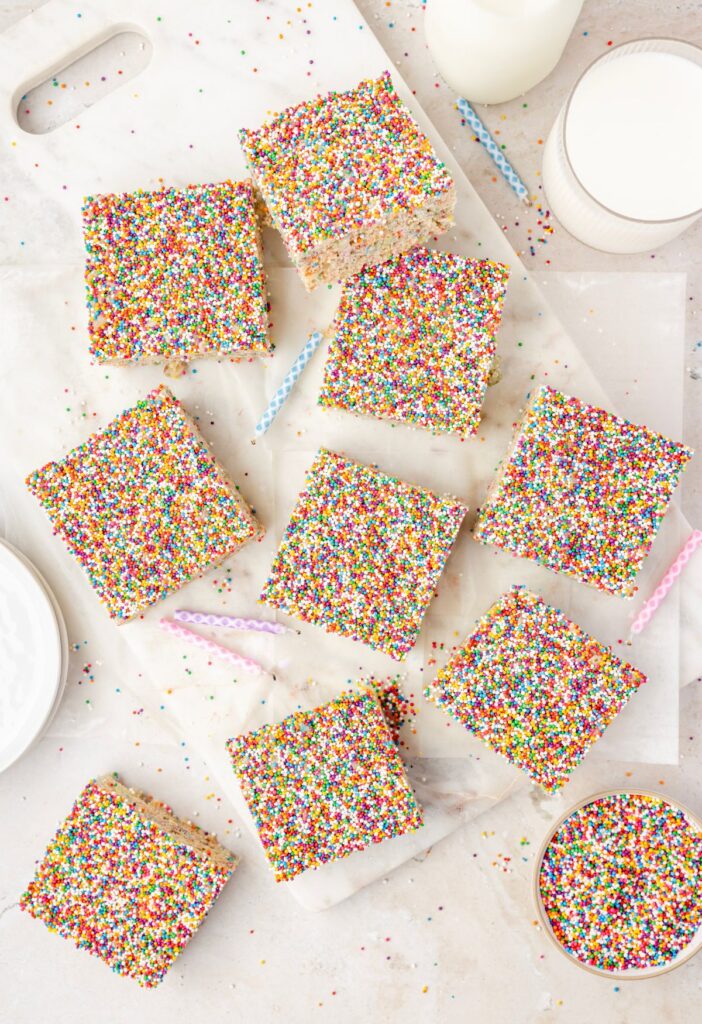 overhead pic of the krispie treats with a bowl of sprinkles and milk next to them