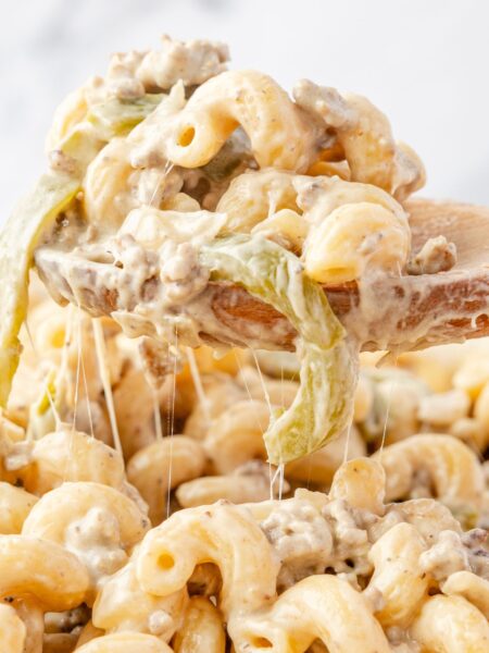 A wooden spoon holding the pasta above the skillet.