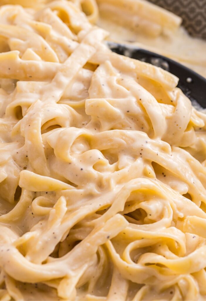 Creamy alfredo sauce and fettuccine pasta in a skillet pan.