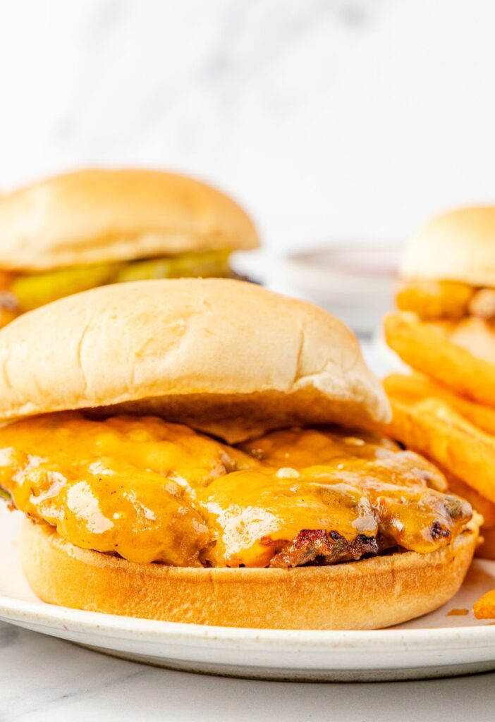 A cheeseburger on a plate with a patty and slice of cheddar cheese