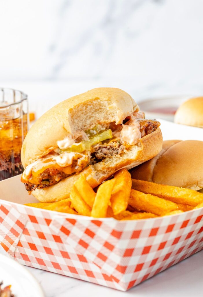 A cheeseburger on a tray with fries and a coke