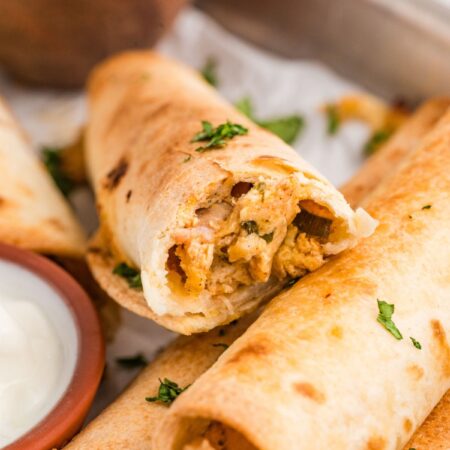 A crispy chicken taquito broken in half to see the chicken filling.