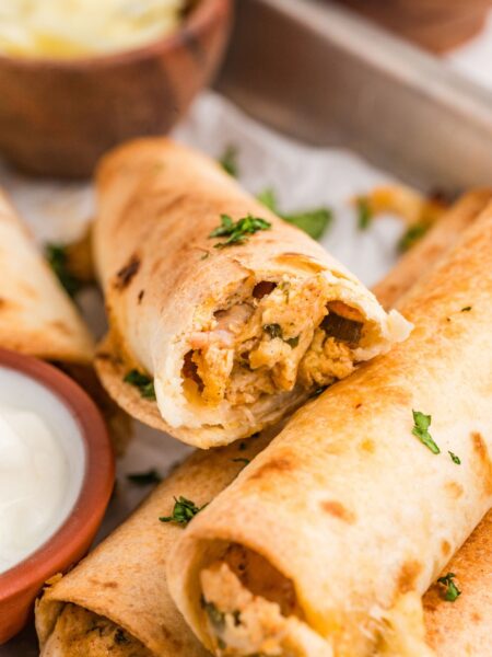 A crispy chicken taquito broken in half to see the chicken filling.