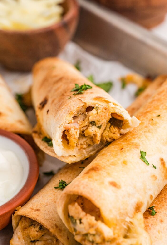 A crispy chicken taquito broken in half to see the chicken filling.