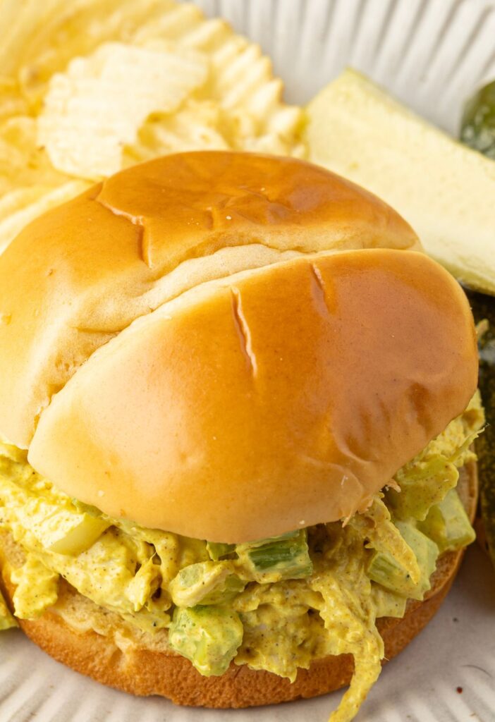 A sandwich of chicken salad on a plate with a pickle