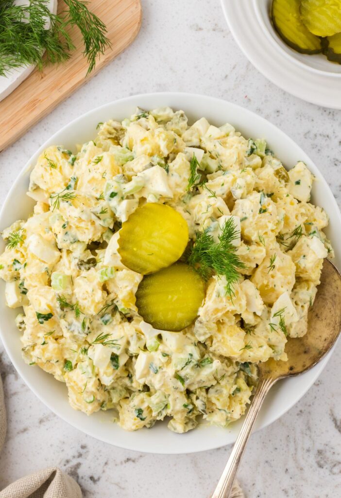 Top view of the serving bowl of potato salad with a serving spoon in it
