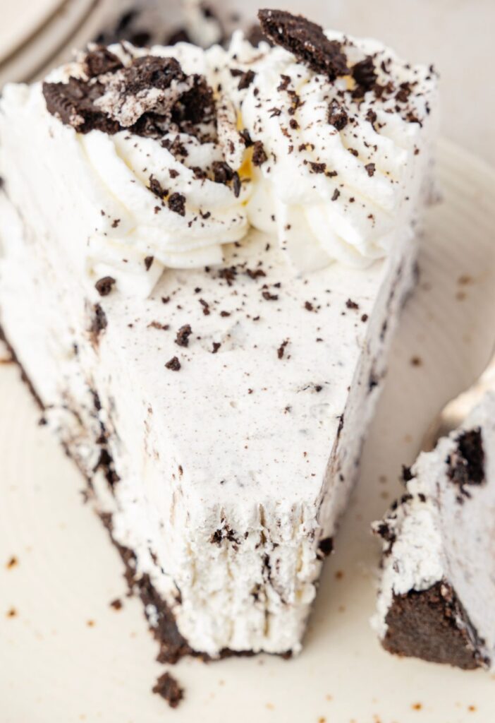 Slice of Oreo cheesecake with a fork next to it with a bite of the cheesecake.