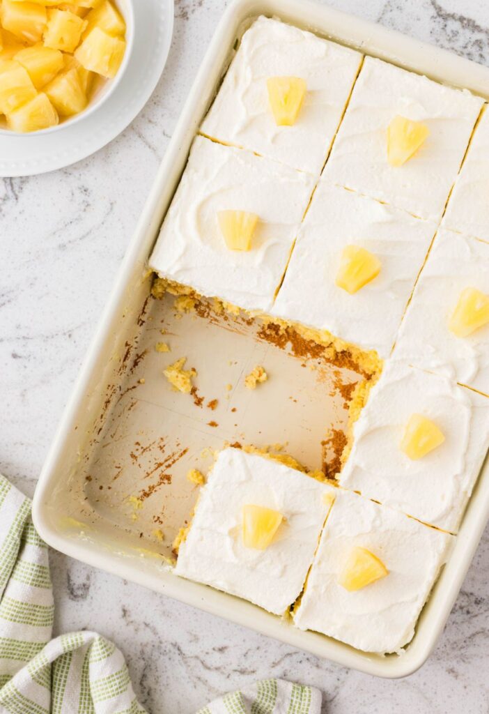 A pan of the baked poke cake with a few pieces taken out of it.