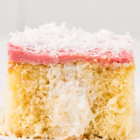 A slice of the cake that is showing the poked holes in the middle with cream filling.