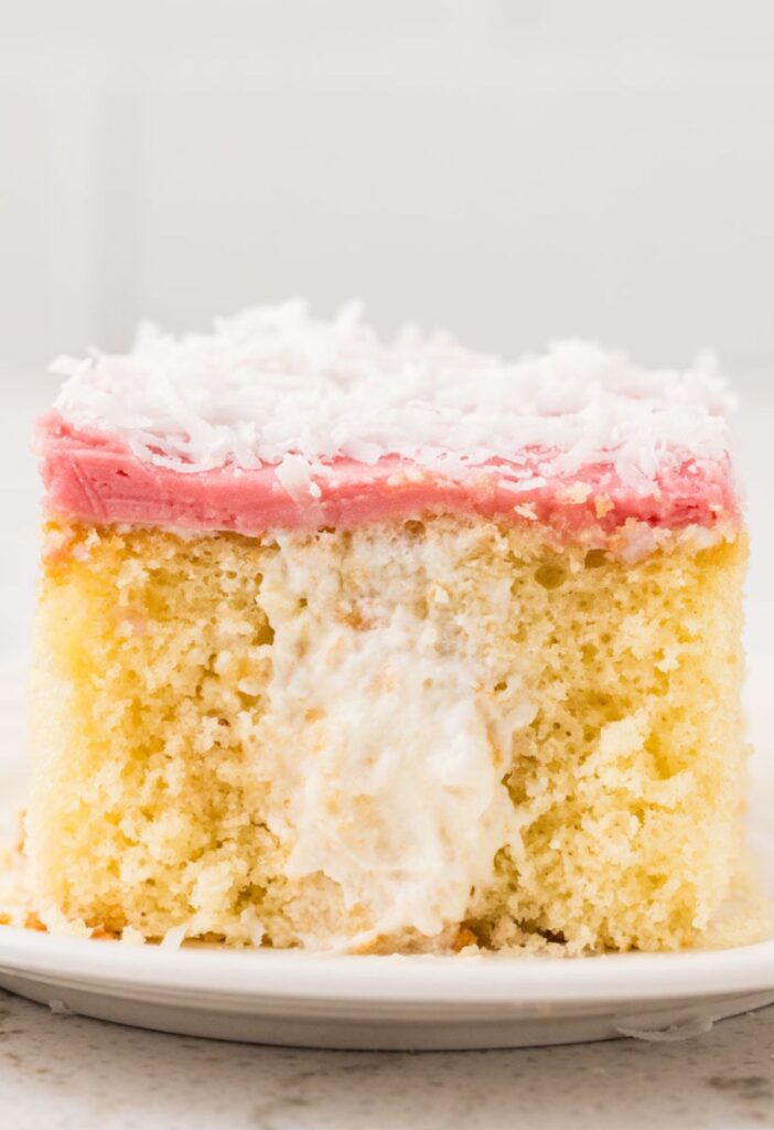 A slice of the cake that is showing the poked holes in the middle with cream filling.