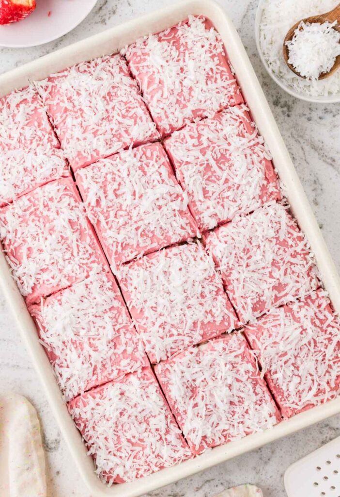 Top view of the pan of cake with pink raspberry frosting and coconut on top.