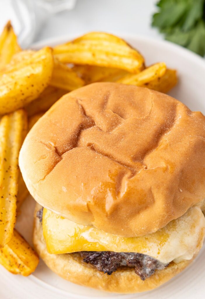 Top view of the butter burger on a plate with a bun and fries next to it.
