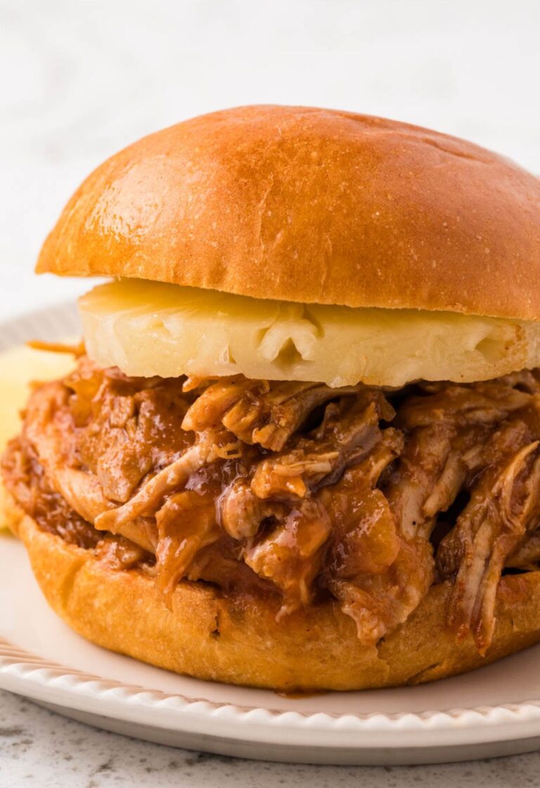 A pulled pork sandwich with a pineapple ring on it.