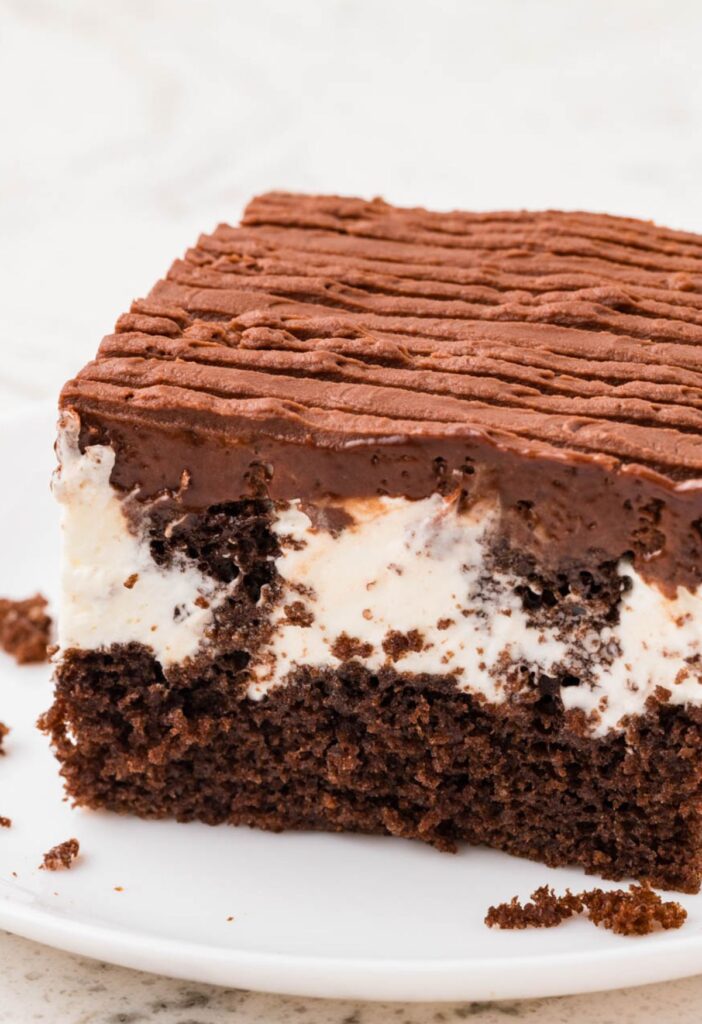 A slice of zingers cake on a white plate showing the poked middle with marshmallow cream.