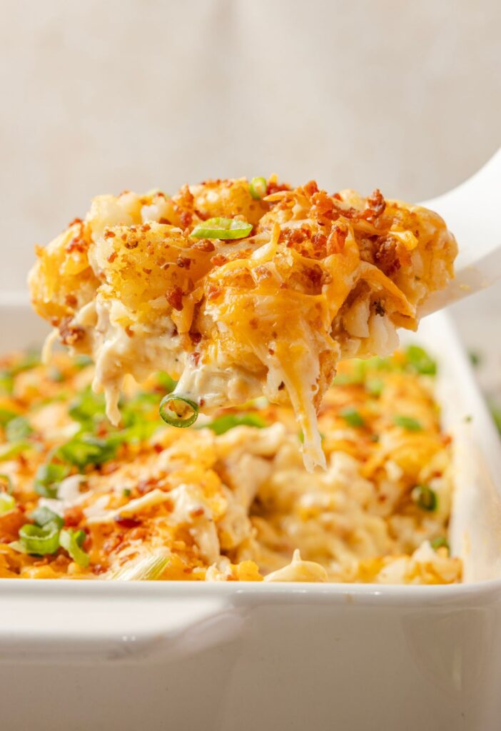a spatula holding up some of the tater tot casserole above the pan