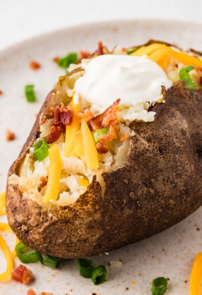 A baked potato ready to eat with all the toppings on it.