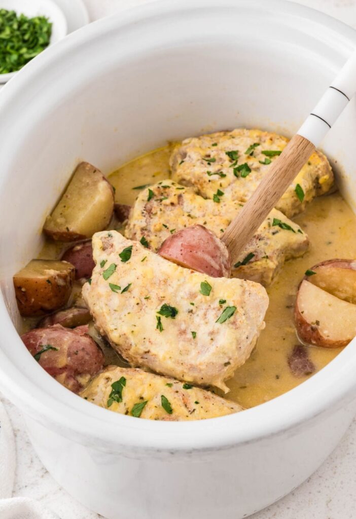 The slow cooker with the ready ranch pork chops ready to serve.