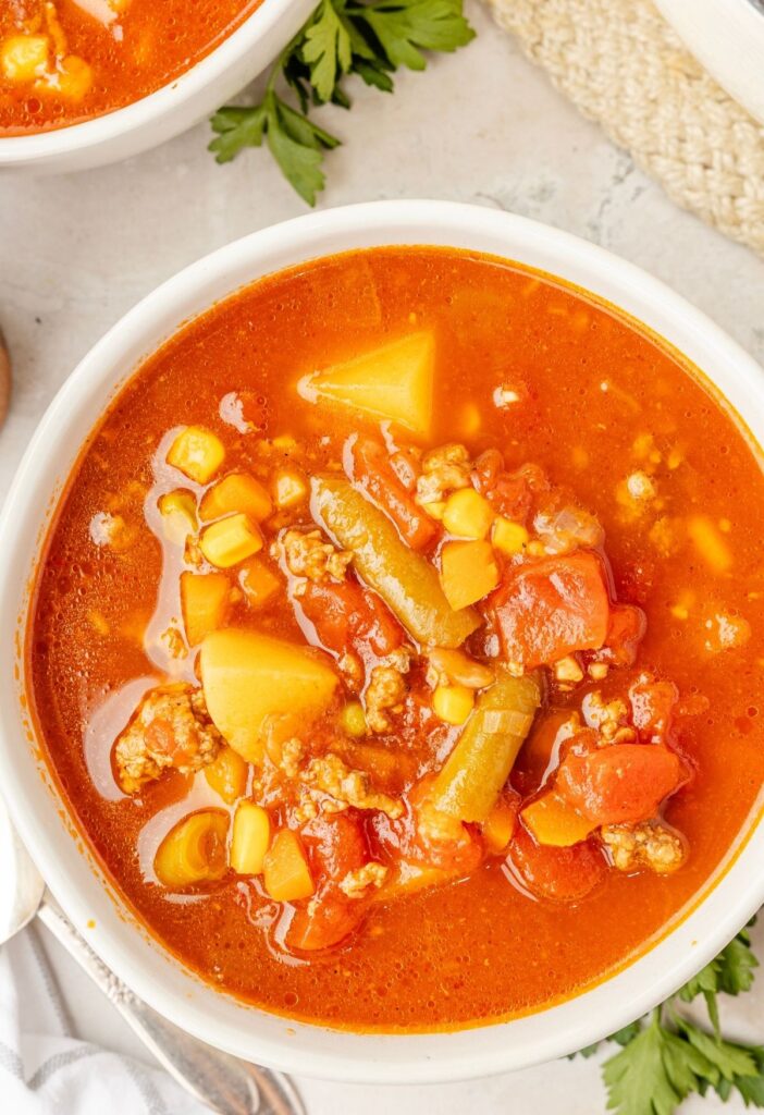 A serving of hamburger soup in a white bowl