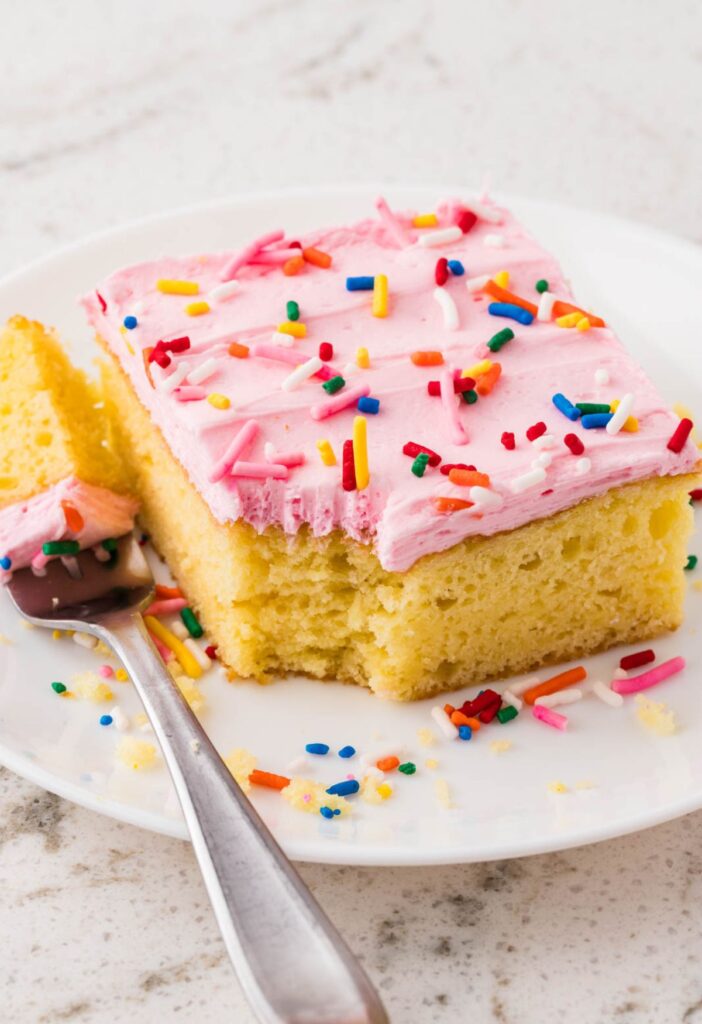 A piece of sugar cookie cake with a fork bite taken out of the corner.