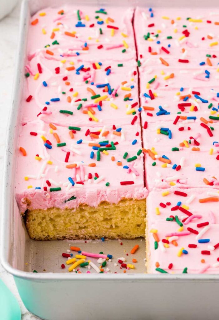 Side view of the cake pan with a corner piece cut out of the cake to see the vanilla cake center.