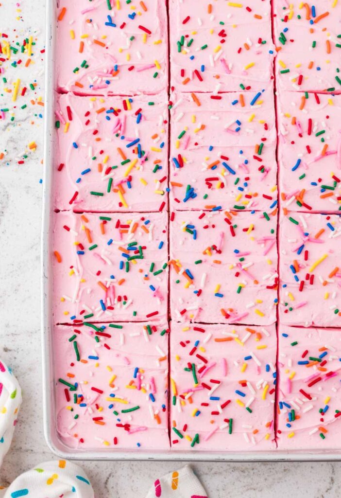 Top view of the baked cake with pink frosting and sprinkles