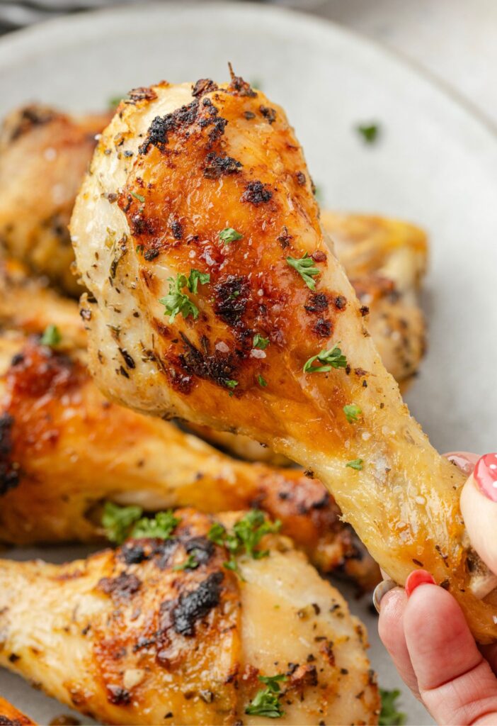 A hand holding a baked chicken drumstick