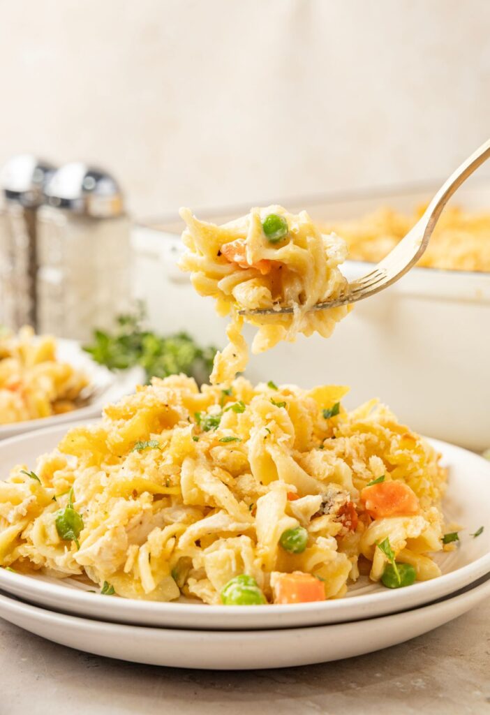 A fork with a bite of the chicken noodle casserole on it.