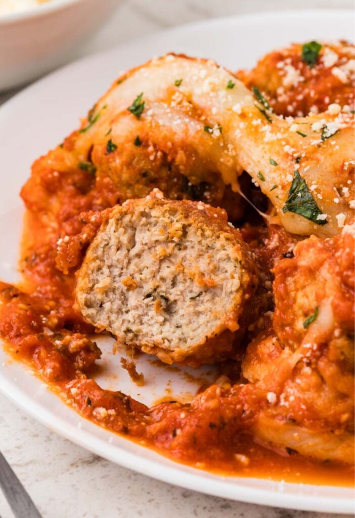 A plate of the chicken parm meatballs with one cut open.