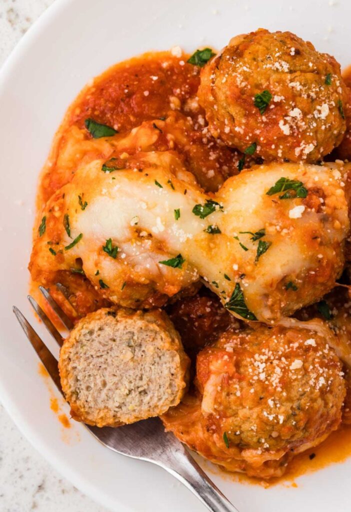A serving plate of the chicken meatballs with a fork